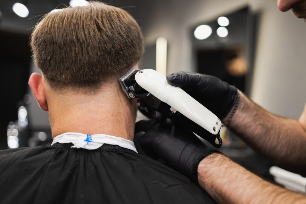 Barber cutting a man's hair with a clipper. Haircut process in salon
