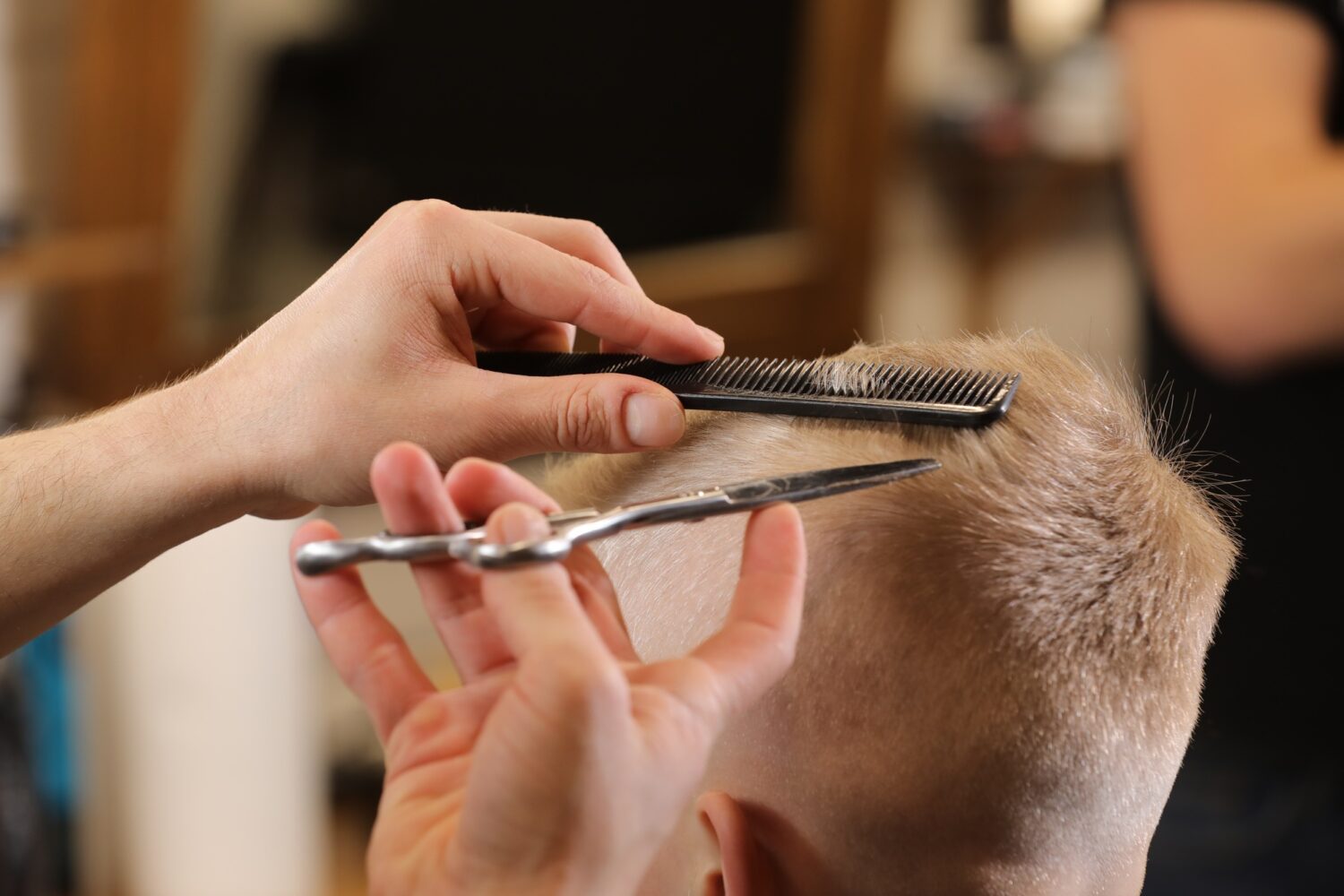 Men's hairstyling, haircutting, in a barber shop or hair salon. Close-up of man hands grooming kid